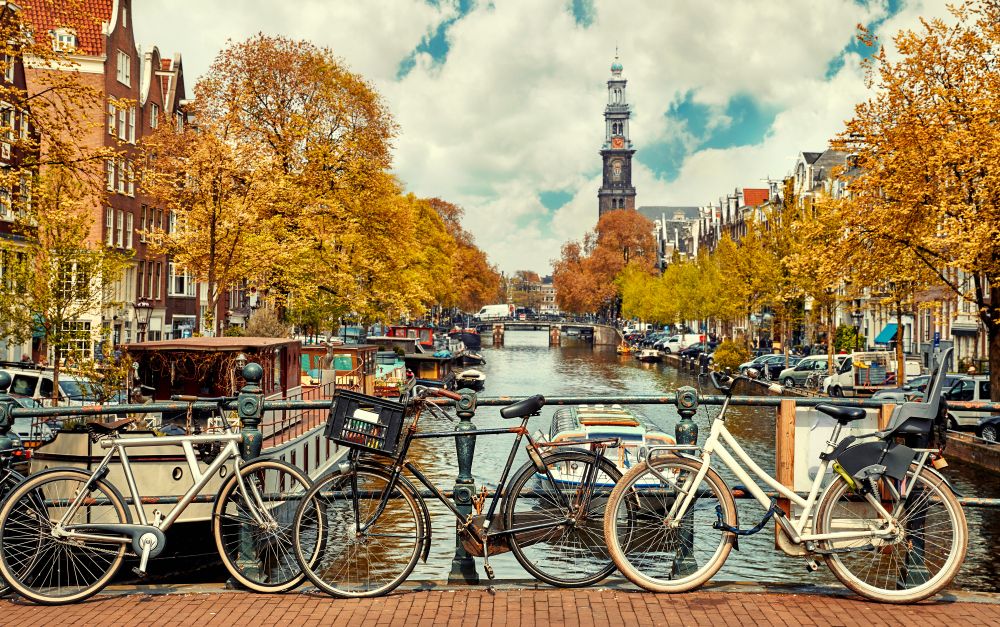 Fall foliage with bicycles on a bridge over the water in Europe.