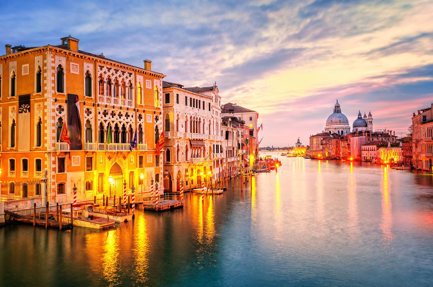 Sunset of European buildings on a waterway with boat docks.