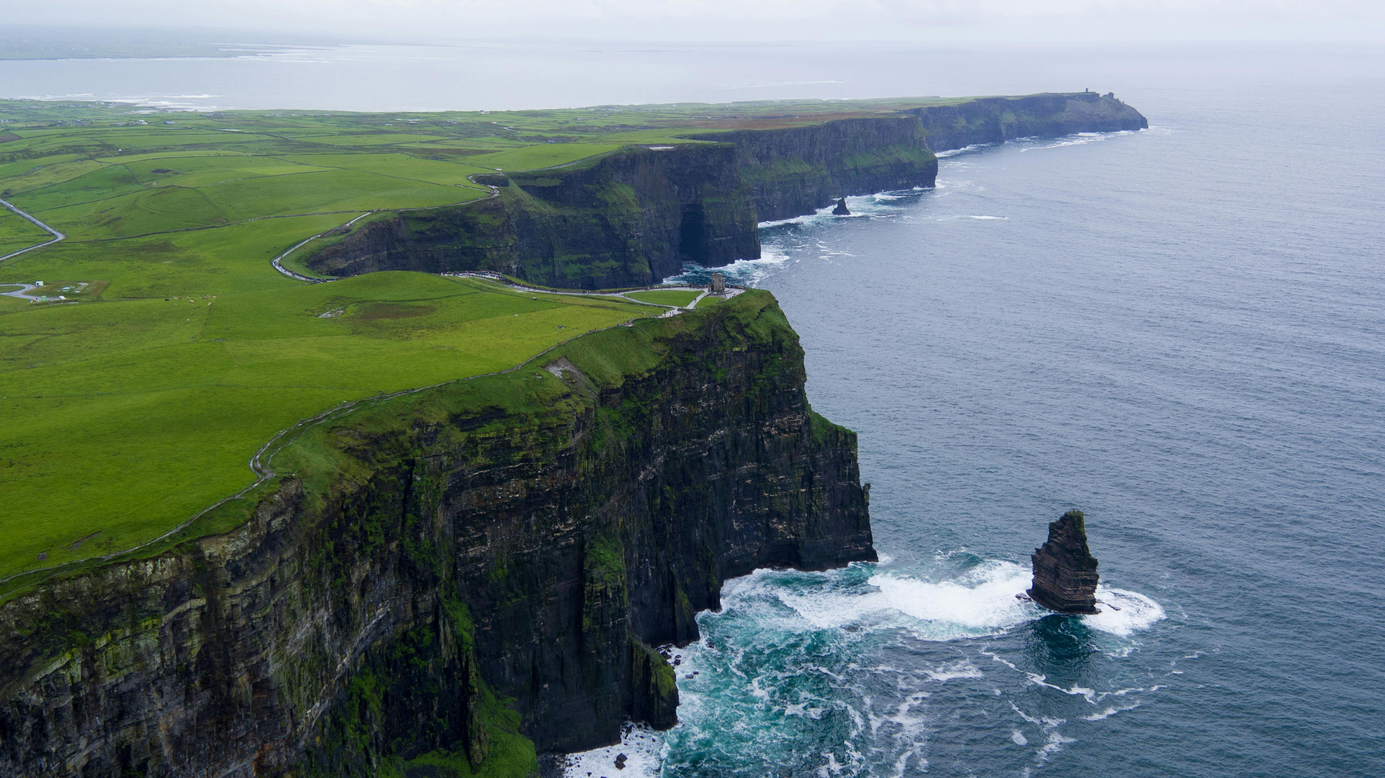 Explore beautiful green pastures of the Ring of Kerry. Cliffs of Ireland overlooking blue calm waters.