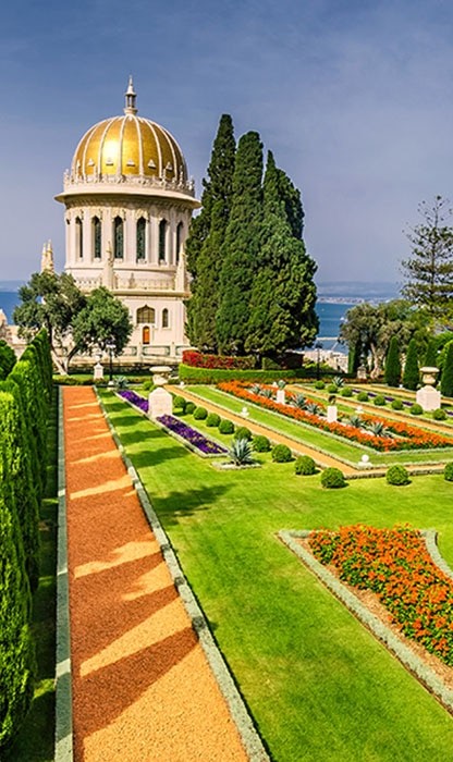 beautifully manicured landscape with floral gardens and a tall round building with a gold and white roof