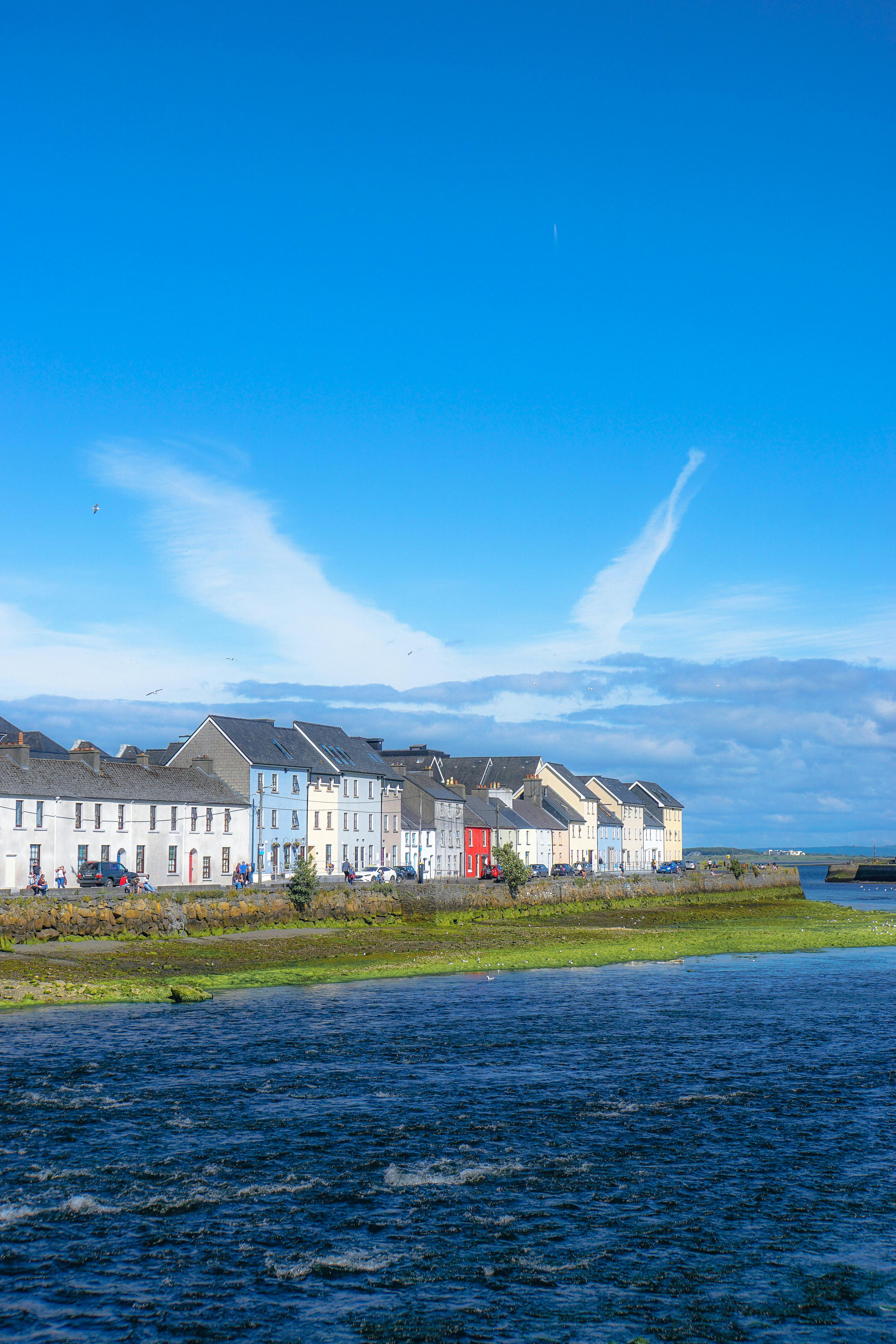 Beautiful scene of old Ireland homes all close to one another overlooking blue calm waters of Ireland. Book DREW Travel Today for your next adventure to Ireland